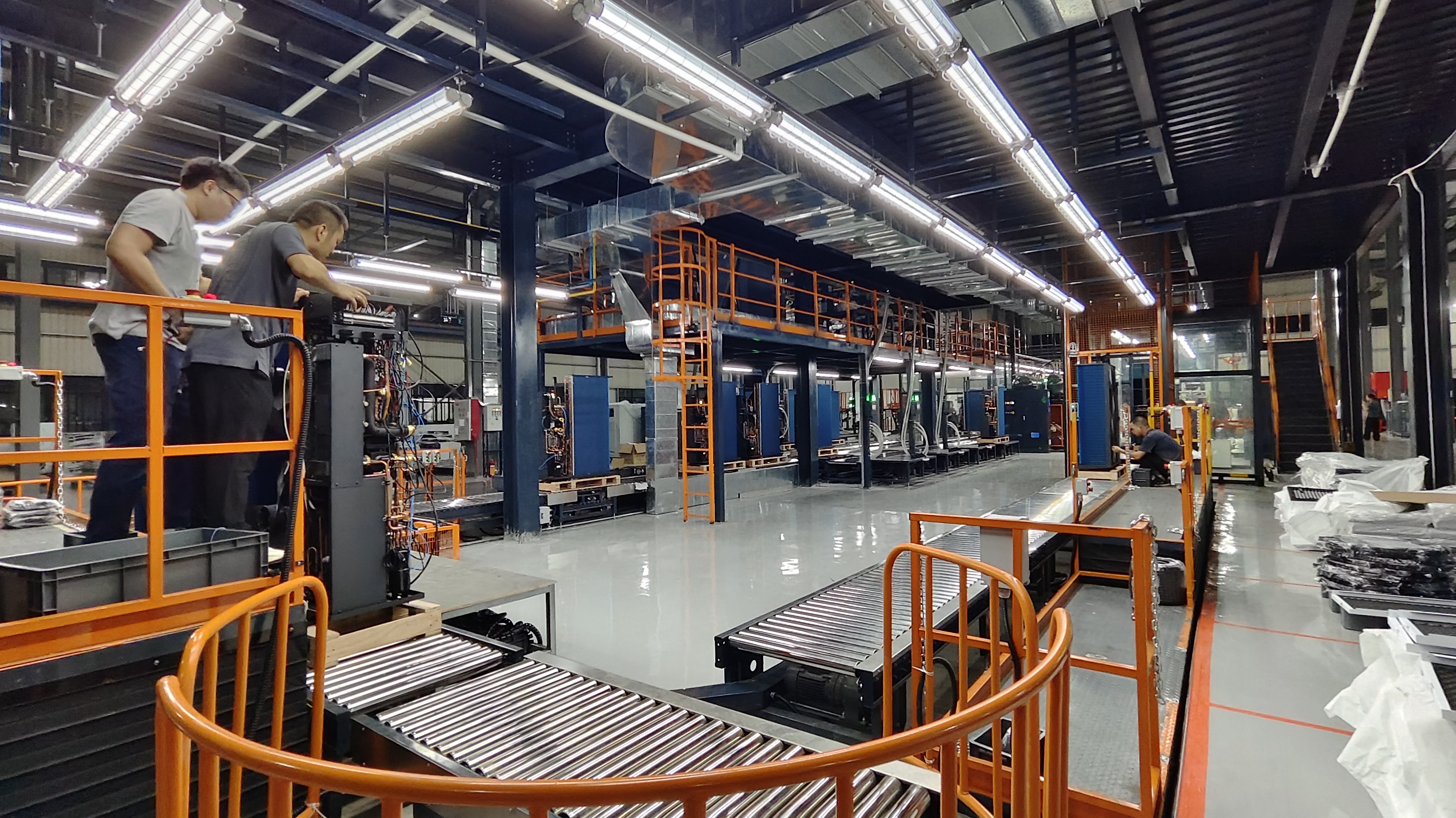 GOODHEAT residential heat pump production line with roller conveyors, assembly stations and orange safety barriers